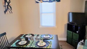 A dining table set for four with a decorative table runner, four plates, and four glasses.