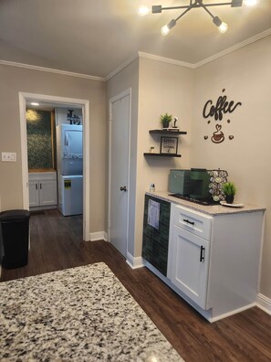 A kitchen with a granite countertop, a dishwasher, and a wall-mounted coffee bar. - FrankleeB Haven Andrews (Andrews)