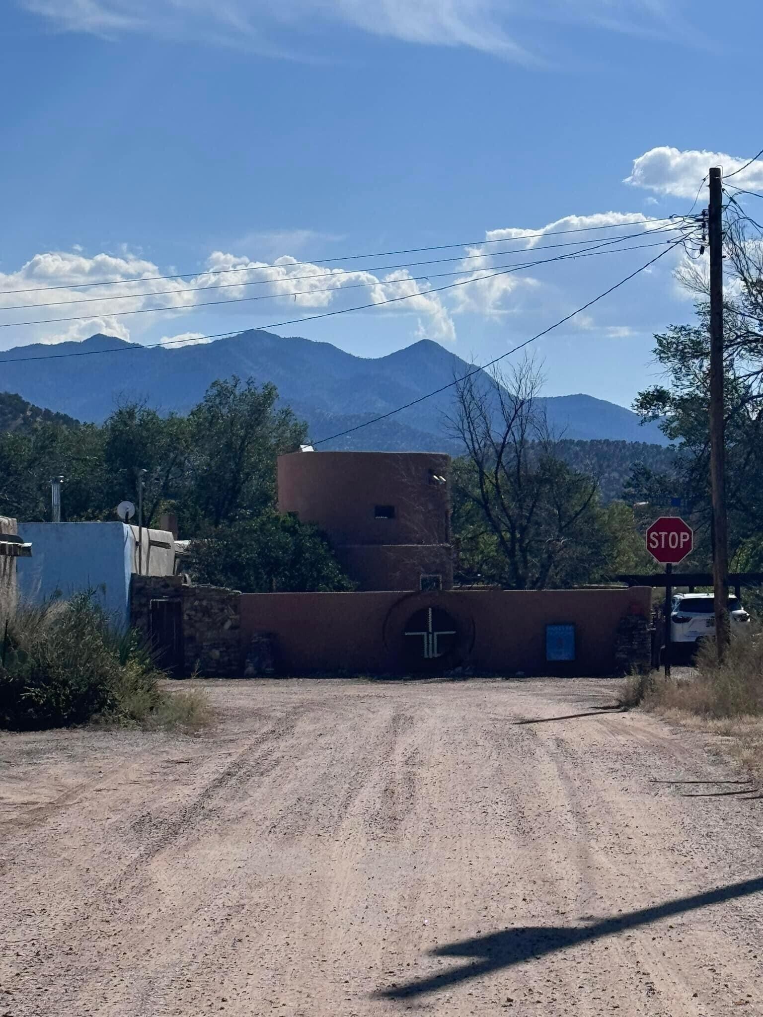 A rural road with a stop sign, a dirt path, and mountains in the background.