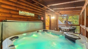 A hot tub in a wooden cabin with a view of the outdoors. - Hidden Cozy Cabin Villa with Hot Tub Close to Everything (Pigeon Forge)