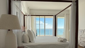 A bedroom with a large bed, a bedside lamp, and a view of the sea. - Hemingway By YellowKey (Guayacanes)