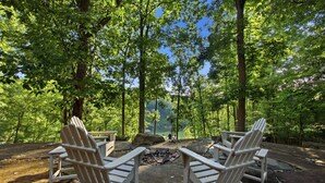 Ein bewaldeter Campingplatz mit Adirondack-Stühlen und einer Feuerstelle.