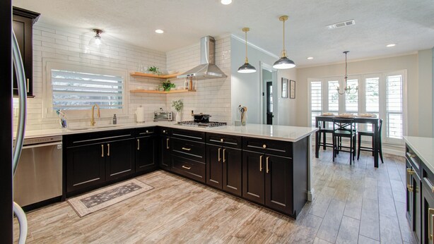 A modern kitchen with dark cabinetry, a large island, and pendant lighting. - Chic TX House w/ Pool and Relaxing Atmosphere (Spring)