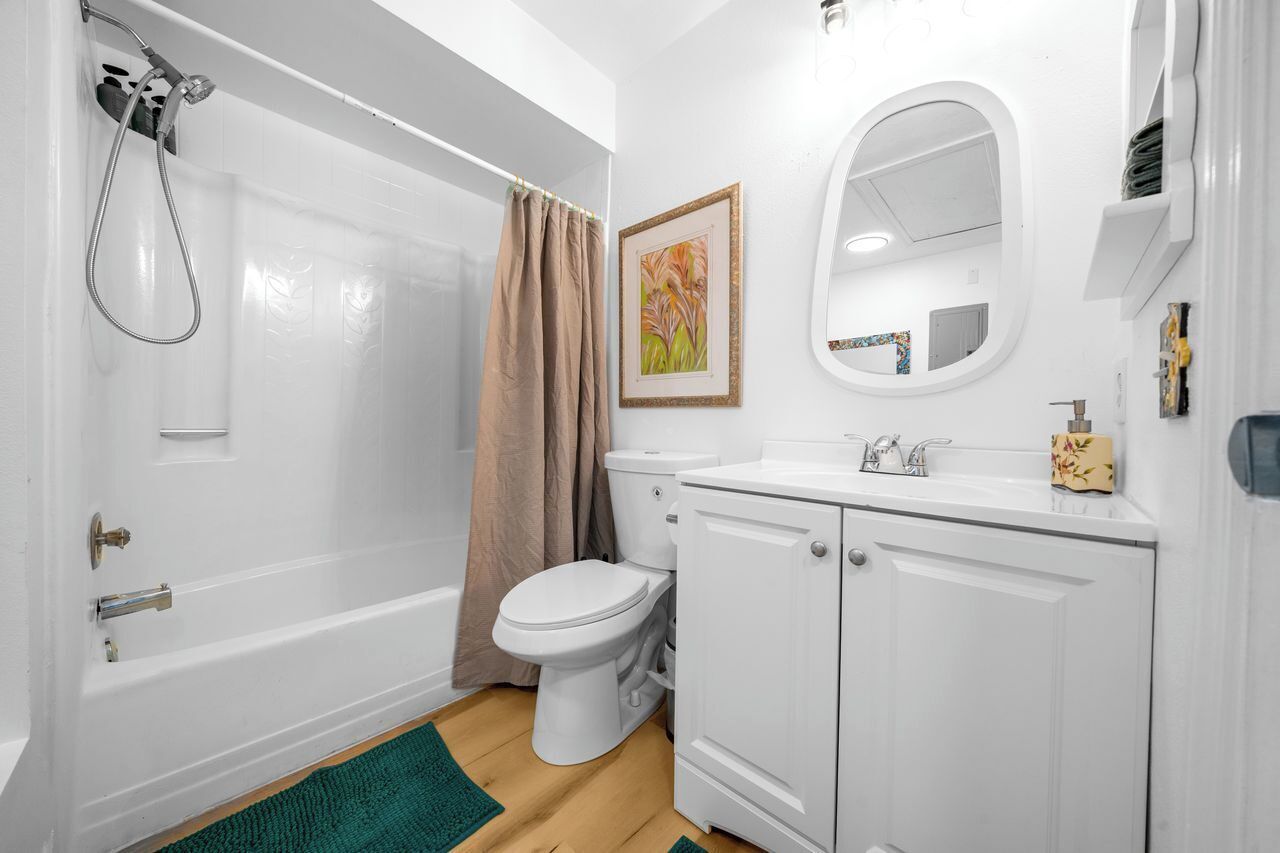 A bathroom with a bathtub, toilet, sink, and a mirror.