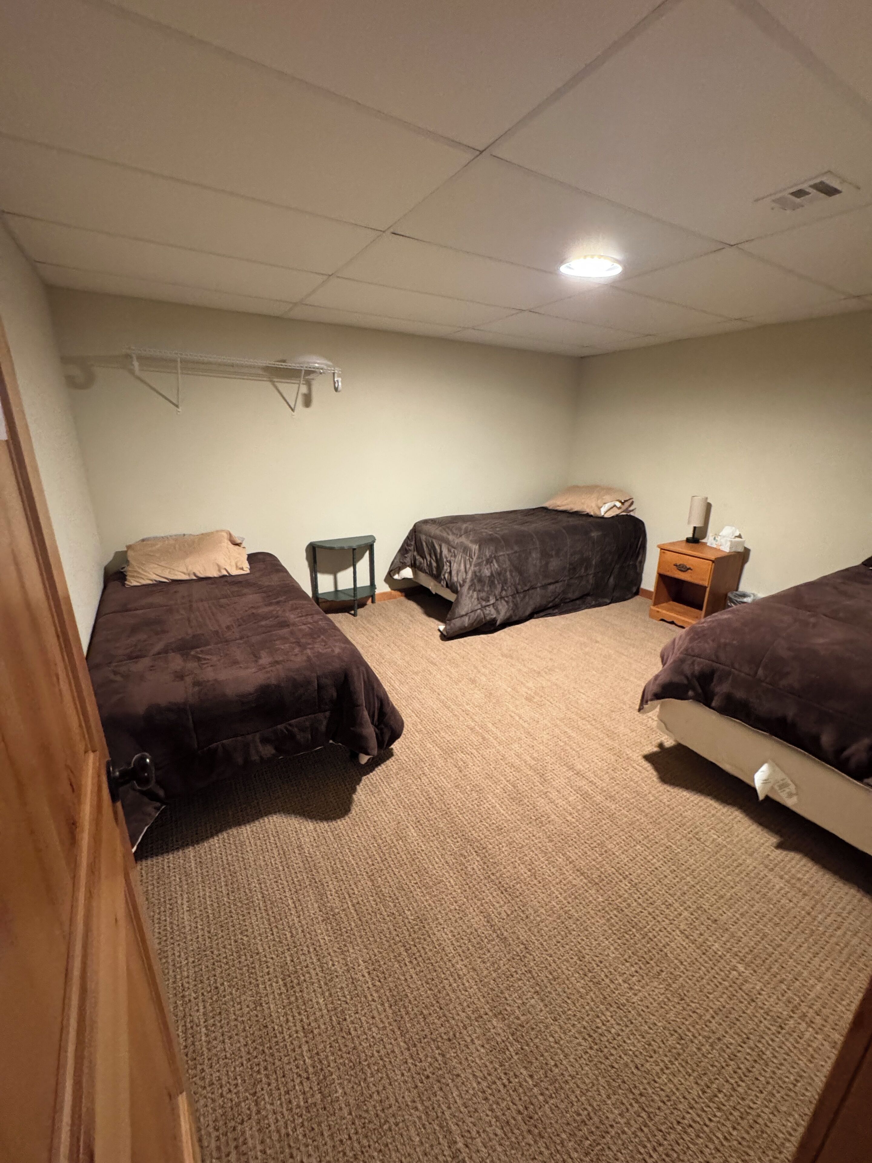 Une chambre avec trois lits, une petite table et une table de chevet avec une lampe.