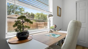 Ein Zimmer mit Schreibtisch, Bonsai-Baum, Globus und einem gerahmten Bild an der Wand.