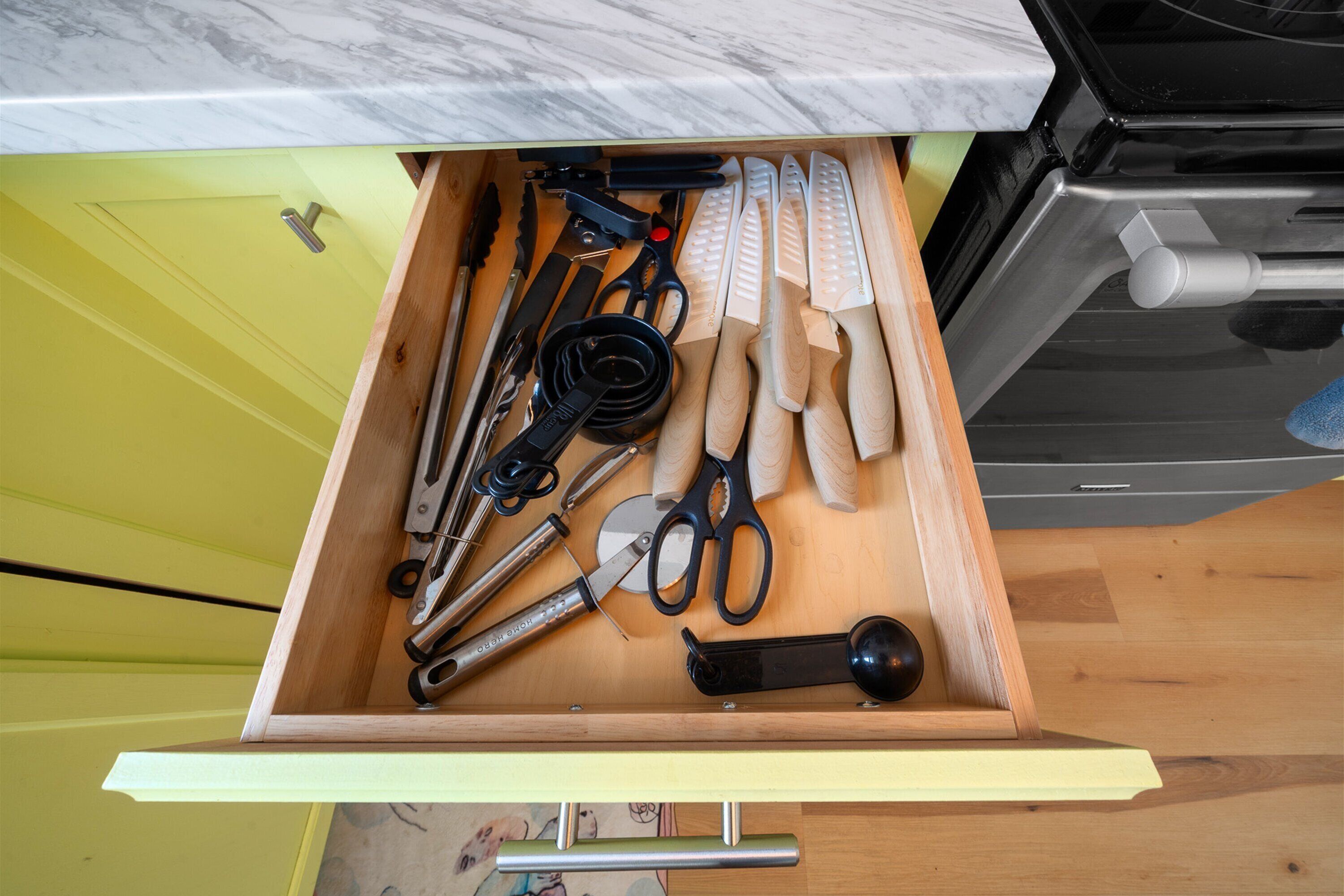 A drawer with various kitchen utensils, including scissors, knives, and a can opener.