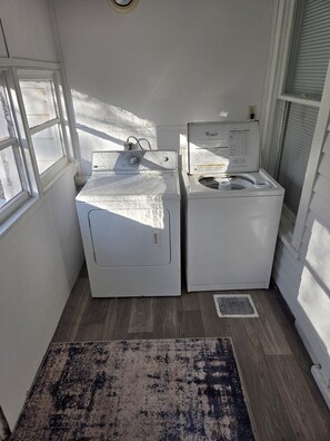A laundry room with two white front-loading washing machines, a small rug, and a window providing natural light. - Cozy 1-bedroom house in lovely Springfield with AC (Springfield)