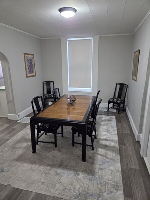 A conference room with a wooden table, six chairs, a large window, and two framed pictures on the walls. - Cozy 1-bedroom house in lovely Springfield with AC (Springfield)