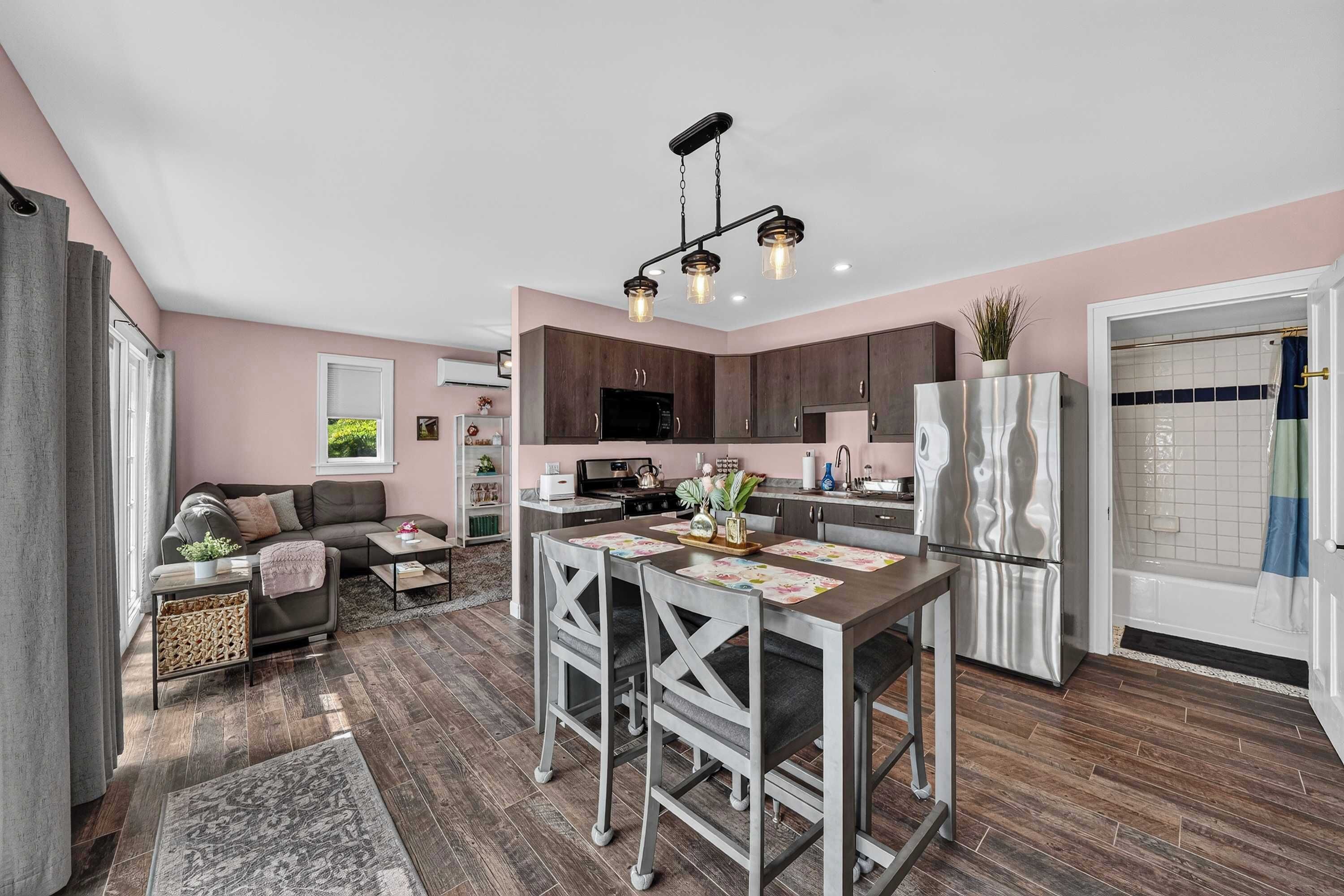 A modern kitchen with dark wood cabinets, a stainless steel refrigerator, and a dining area with a table and chairs.