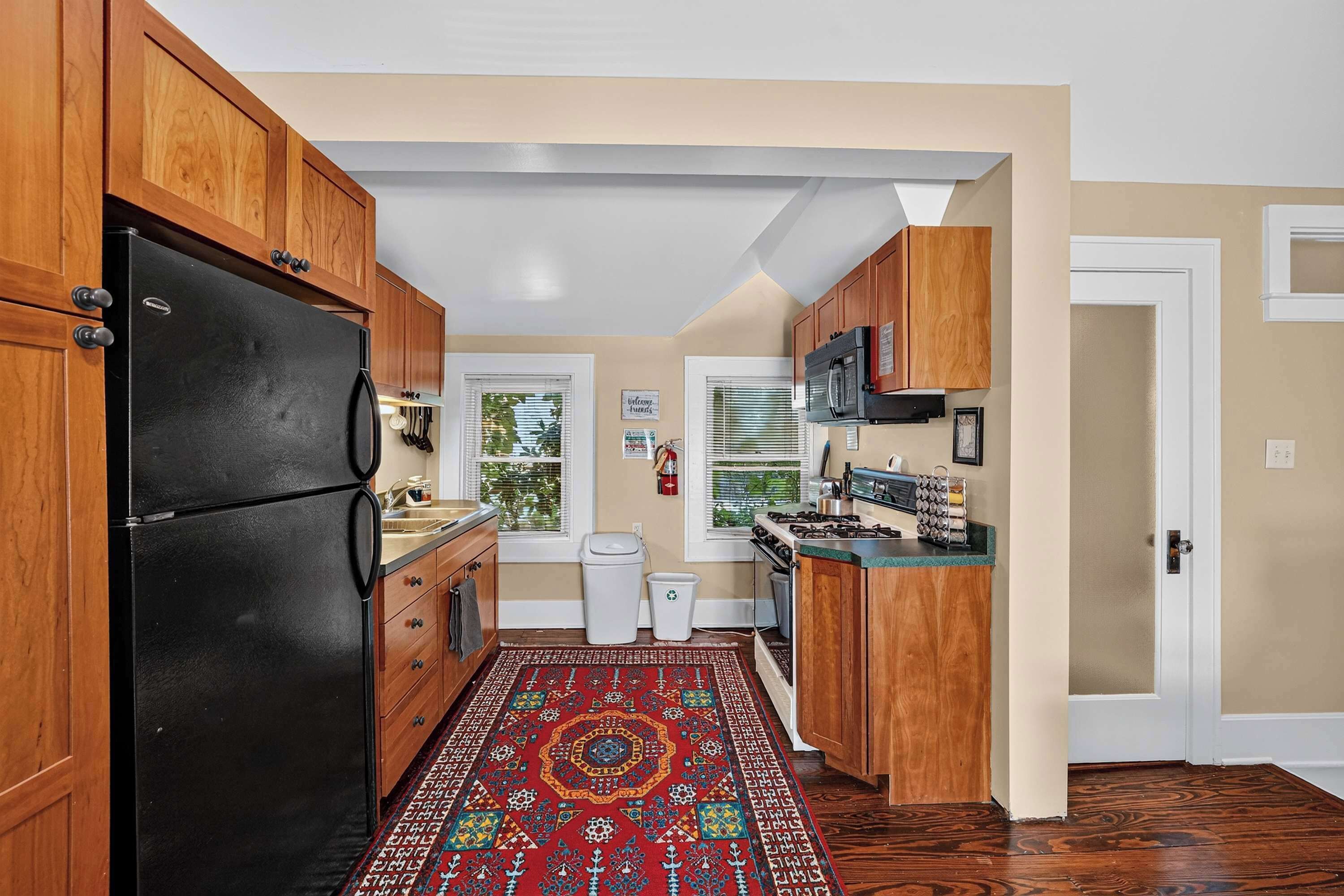 A kitchen with wooden cabinets, a black refrigerator, a stove, and a microwave.