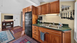 Una cocina moderna con armarios de madera, un refrigerador negro, un lavamanos y una encimera.