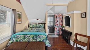 Un dormitorio con cama, escritorio, silla, ventana con persianas y puerta que da a un baño.