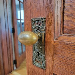 A wooden door with an ornate brass doorknob and a decorative metal plate. - Historic South Bend Home: Art, Comfort & Charm (South Bend)