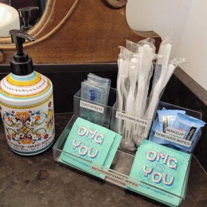 A bathroom counter with a hand soap dispenser, toothbrushes, toothpaste, and antiperspirant wipes. - Historic South Bend Home: Art, Comfort & Charm (South Bend)