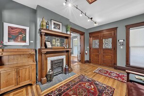 A spacious living room with a fireplace, wooden furniture, and a large rug. - Historic South Bend Home: Art, Comfort & Charm (South Bend)