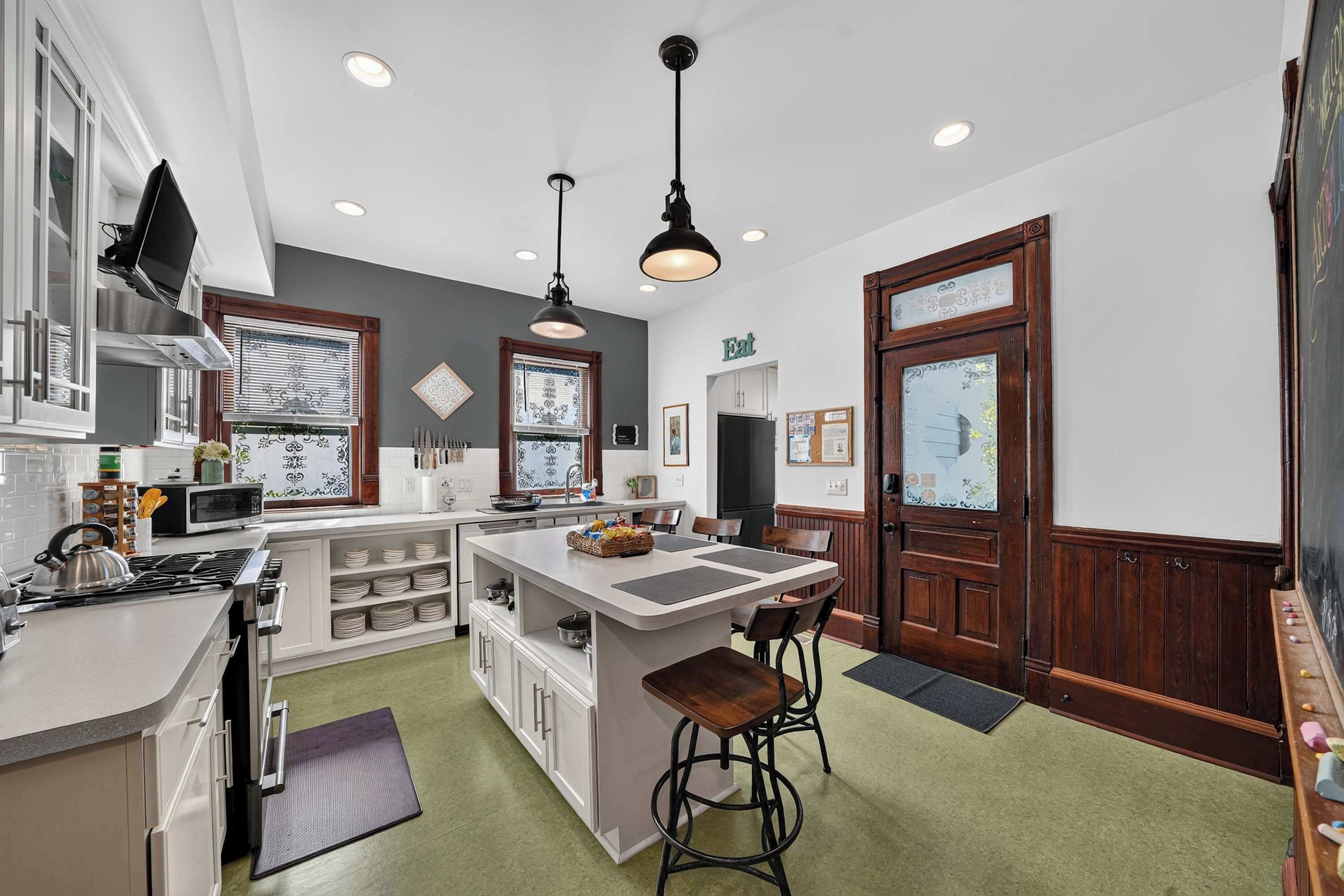 A modern kitchen with a central island, bar stools, and a dining area.
