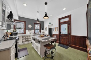 A modern kitchen with a central island, bar stools, and a dining area. - Historic South Bend Home: Art, Comfort & Charm (South Bend)