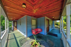 A covered porch with a swing seat and a table with a potted plant. - Historic South Bend Home: Art, Comfort & Charm (South Bend)