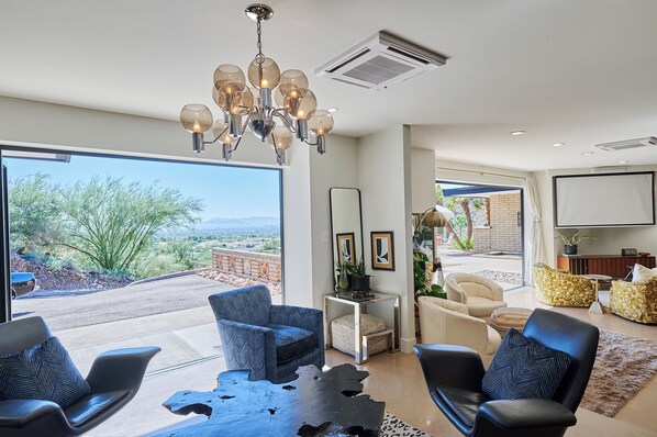 A spacious living room with a large window, a chandelier, and a view of the outdoors. - Paradise Valley Private Hilltop Estate--Entertainers Dream (Paradise Valley)