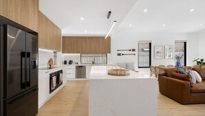 Una cocina moderna con una isla central, un área de comedor con un sofá de cuero marrón y vistas al exterior.