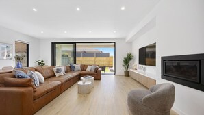 Una sala de estar moderna con un sofá de cuero marrón, un sillón gris, una mesa de centro y una chimenea.