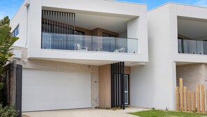 Una casa moderna de dos pisos con garaje, ventanas amplias y un balcón.