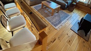 A cozy cabin interior with a wooden floor, a large gray sectional sofa, a wooden coffee table, and a dining table with chairs. - Charming 1 BR Cabin at Persimmon & Pine Hollow- Secluded Feel, Close to Town (Dublin)