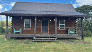 A log cabin with a porch, two windows, and a door. - Charming 1 BR Cabin at Persimmon & Pine Hollow- Secluded Feel, Close to Town (Dublin)