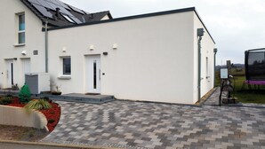 A modern building with a flat roof, a white exterior, and a paved driveway leading to a door marked with the number 13. - Quiet apartment in the green Kreischa near Dresden (Kreischa)