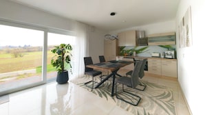 A modern kitchen with a dining area, a large window, and a potted plant. - Quiet apartment in the green Kreischa near Dresden (Kreischa)