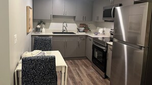 A compact kitchen with grey cabinets, a stainless steel refrigerator, and a microwave. - Modern 1BD Suite•5 star Comfort•Beaumont•Edmonton (Beaumont)