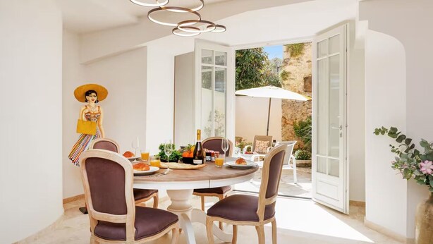 Un comedor con una mesa redonda, sillas y una figura decorativa.