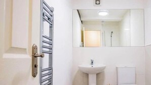 Kylpyhuone, jossa on valkoinen pesuallas, peili ja wc-istuin.