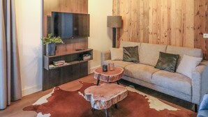 Uma sala de estar com televisão de tela plana, um sofá, uma mesa de centro e uma parede de madeira.
