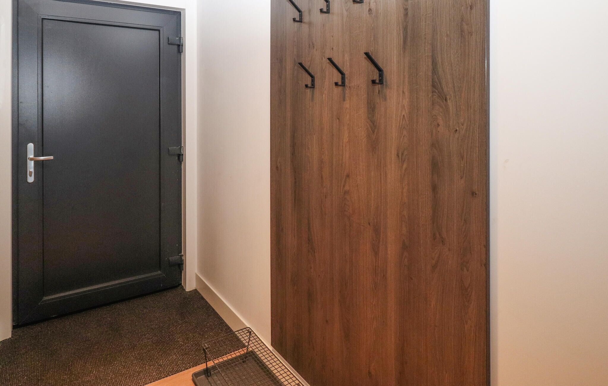 Um corredor com uma porta de madeira escura e uma parede de madeira com ganchos.