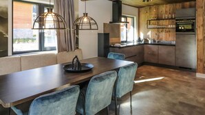 Eine moderne Küche mit Holzarbeitsplatte, eingebautem Ofen und einer Essecke mit langem Tisch und blauen Stühlen.