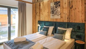 Ein Hotelzimmer mit einer Holzwand, einem großen Bett mit zwei Kissen, einem Nachttisch und einem Fenster mit Vorhängen.