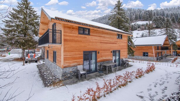 Eine Holzhütte mit Steinfundament, einem Balkon und einer Terrassenfläche.