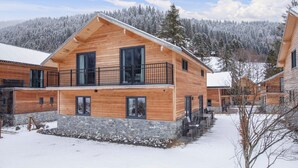 Eine Holzhütte mit Steinuntergrund, großen Fenstern und einem Balkon.