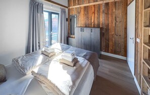 Ein Schlafzimmer mit einem Bett, einem Kleiderschrank und einem Fenster mit Vorhängen.