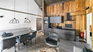 Une cuisine moderne agrémentée d’éléments en bois, un coin repas avec une table et des chaises, et un extincteur visible.