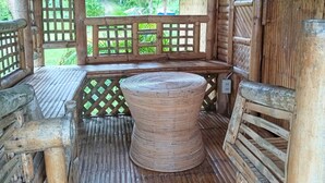 A rustic wooden structure with a thatched roof, a woven bench, and a decorative mat. - Tay Deling's (El Nido)