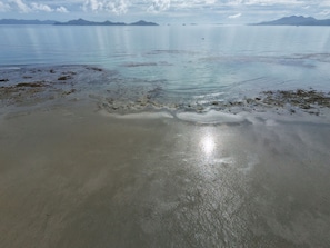 A beach with calm water, distant mountains, and a clear sky. - Tay Deling's (El Nido)