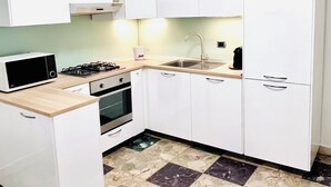 Une cuisine moderne avec des meubles blancs, un four à micro-ondes, une cuisinière et un évier.