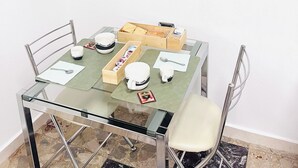 Un coin repas avec une table en verre, des chaises et un téléviseur à écran plat fixé au mur.