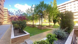 Une cour avec une pelouse, des arbres et des jardinières en briques.