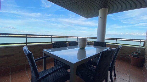 Un balcon avec une table et des chaises, donnant sur une étendue d’eau.