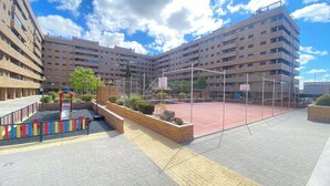 Un immeuble résidentiel à plusieurs étages doté d’un terrain de basketball et d’une aire de jeux.