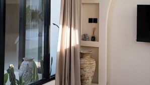 Un intérieur moderne avec une grande fenêtre, un banc incurvé et des vases décoratifs.